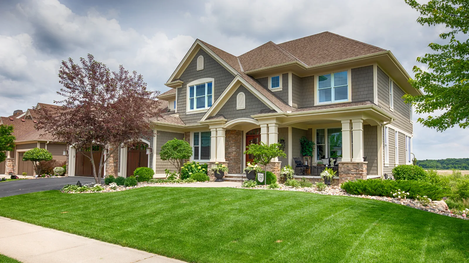 Brown hip shingle roof over a craftsman style two-story with gray shakes