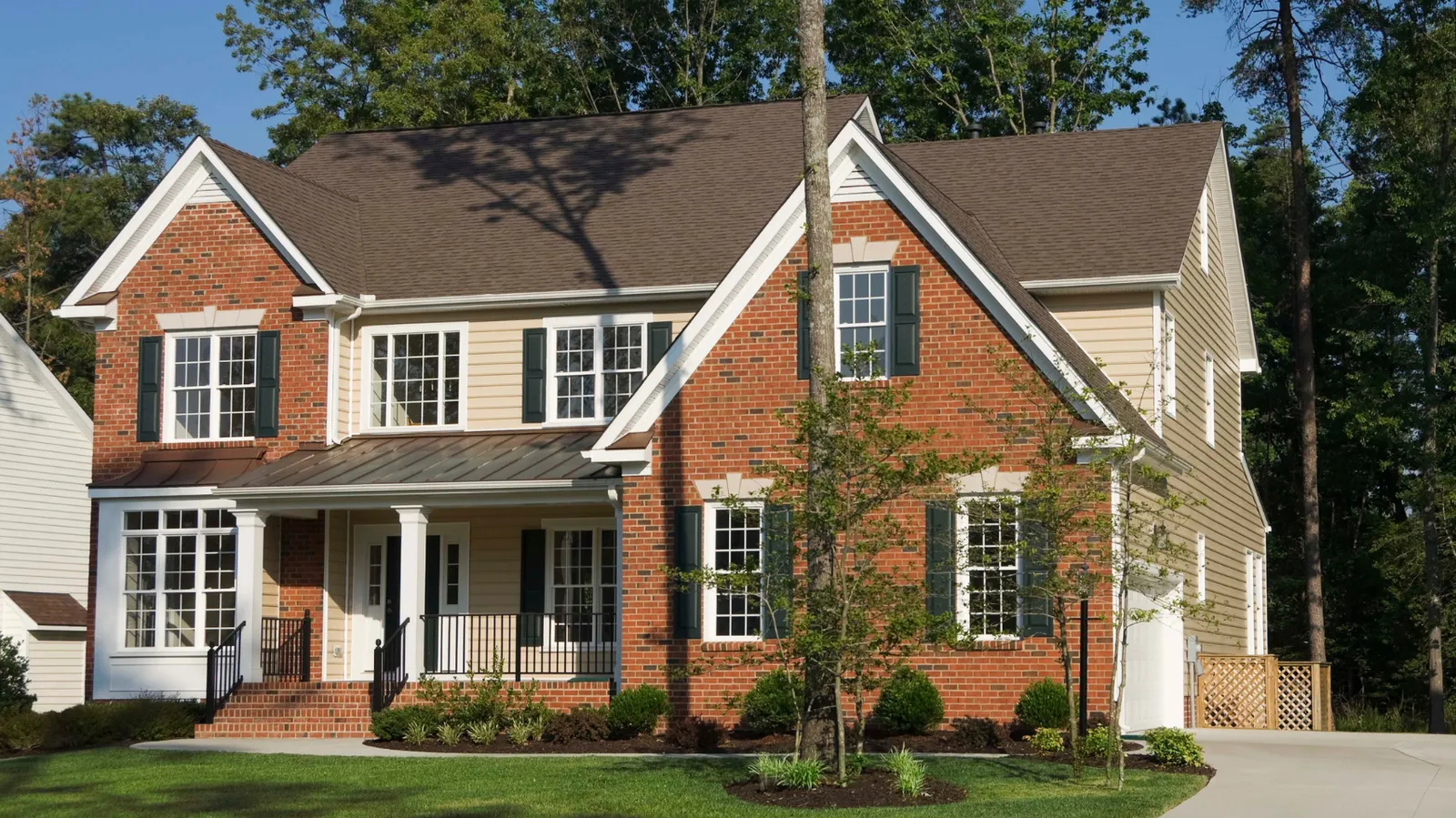 Brown asphalt shingle roof on a red brick and siding two-story