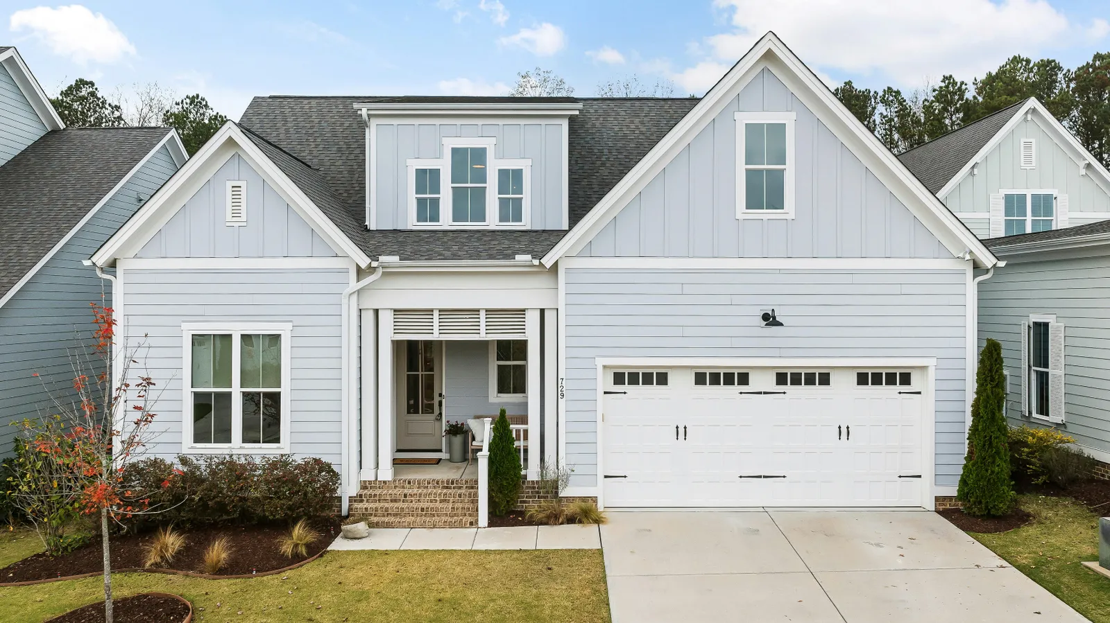 Gray shingle roof and white garage door on a light blue siding home
