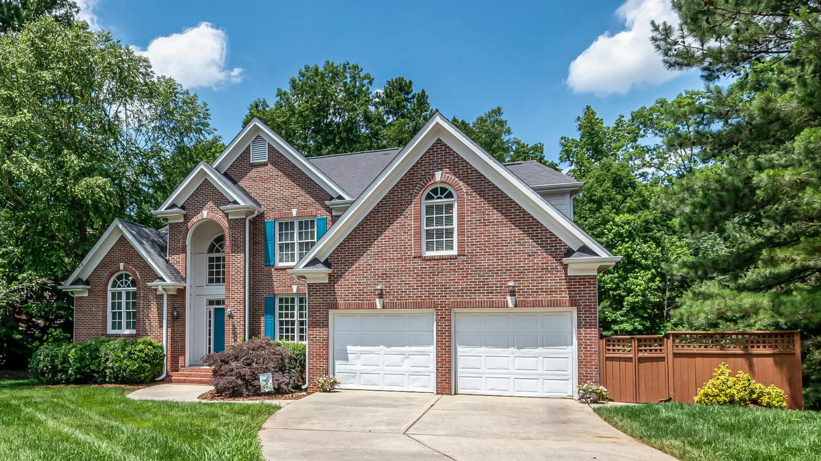 Gray shingle roof and two garage doors on a brick two-story home