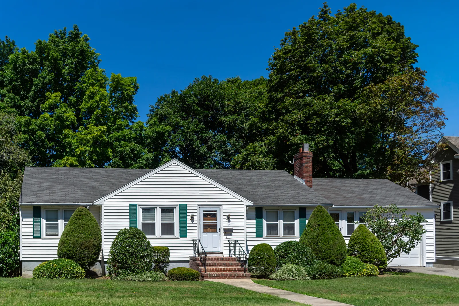 Dark asphalt shingle roof and brick chimney on a white house