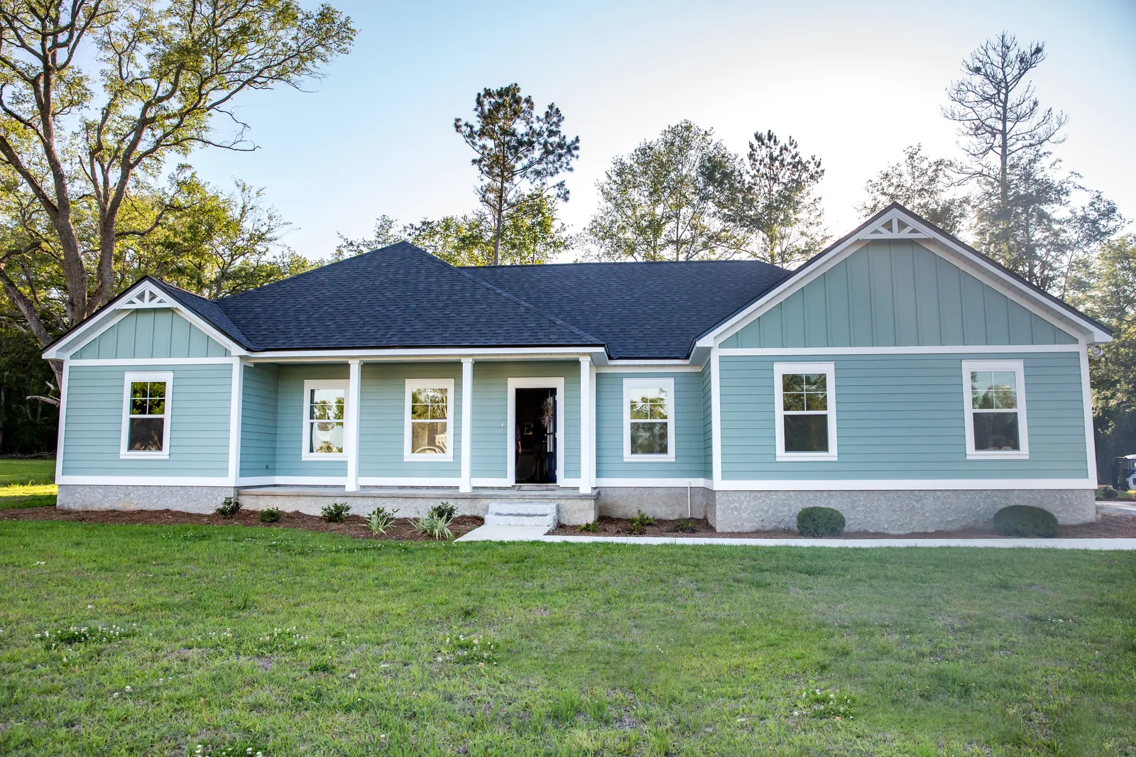 Light blue home with dark asphalt shingle roof and front porch