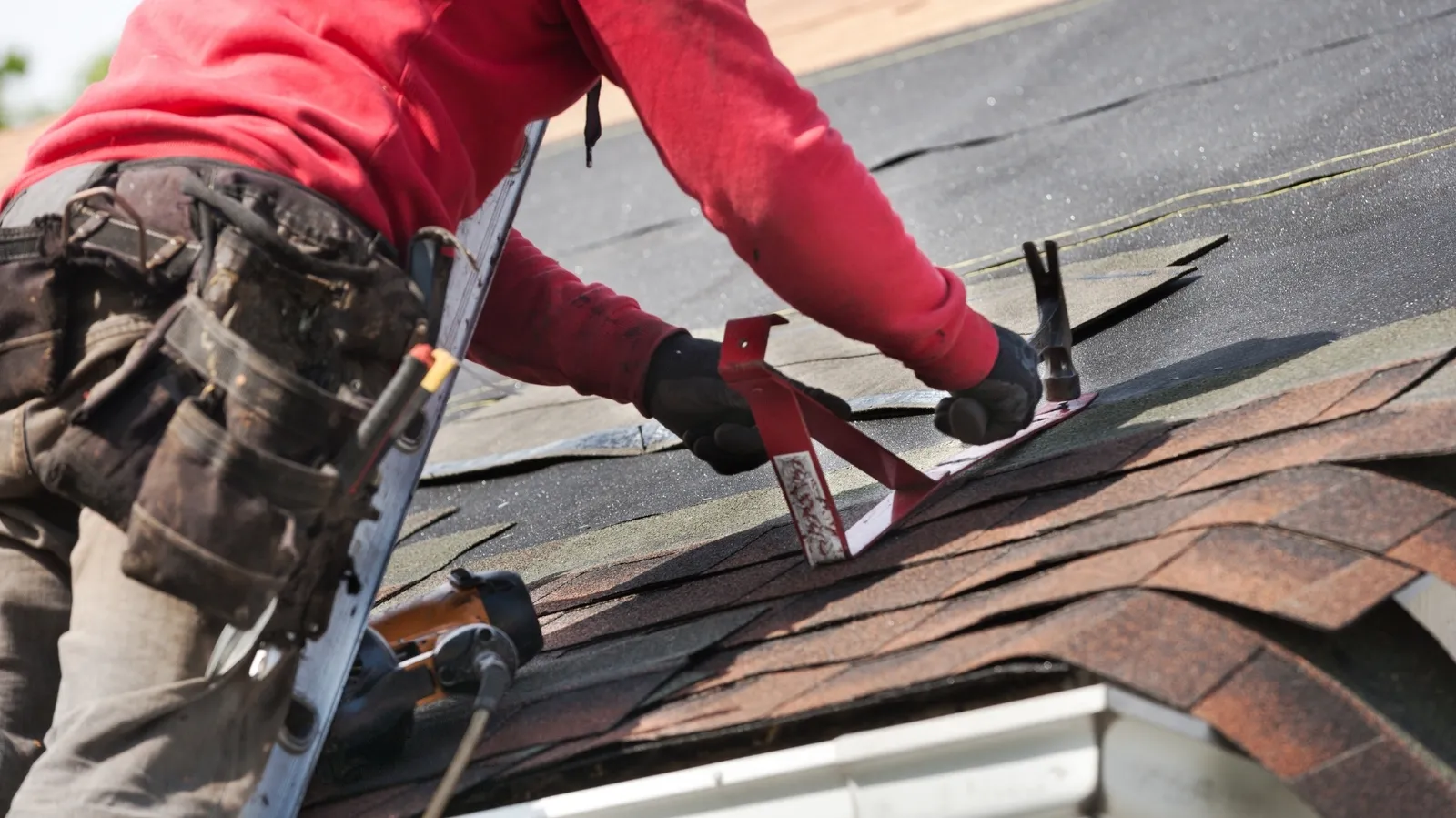 New shingles receiving a roof bracket hammered in by a roofer