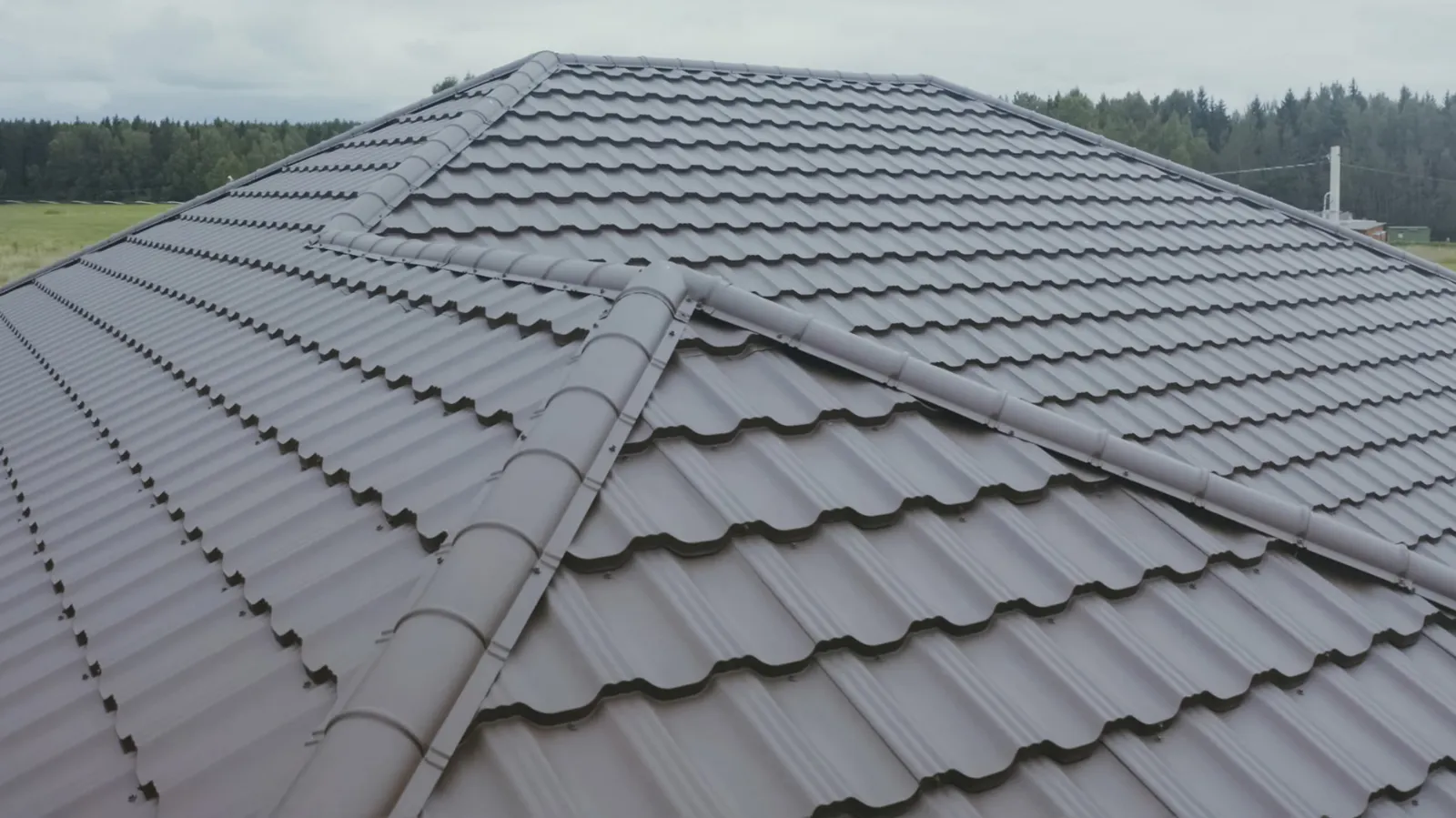 Hip roof covered in brown metal tile roofing with ridge caps