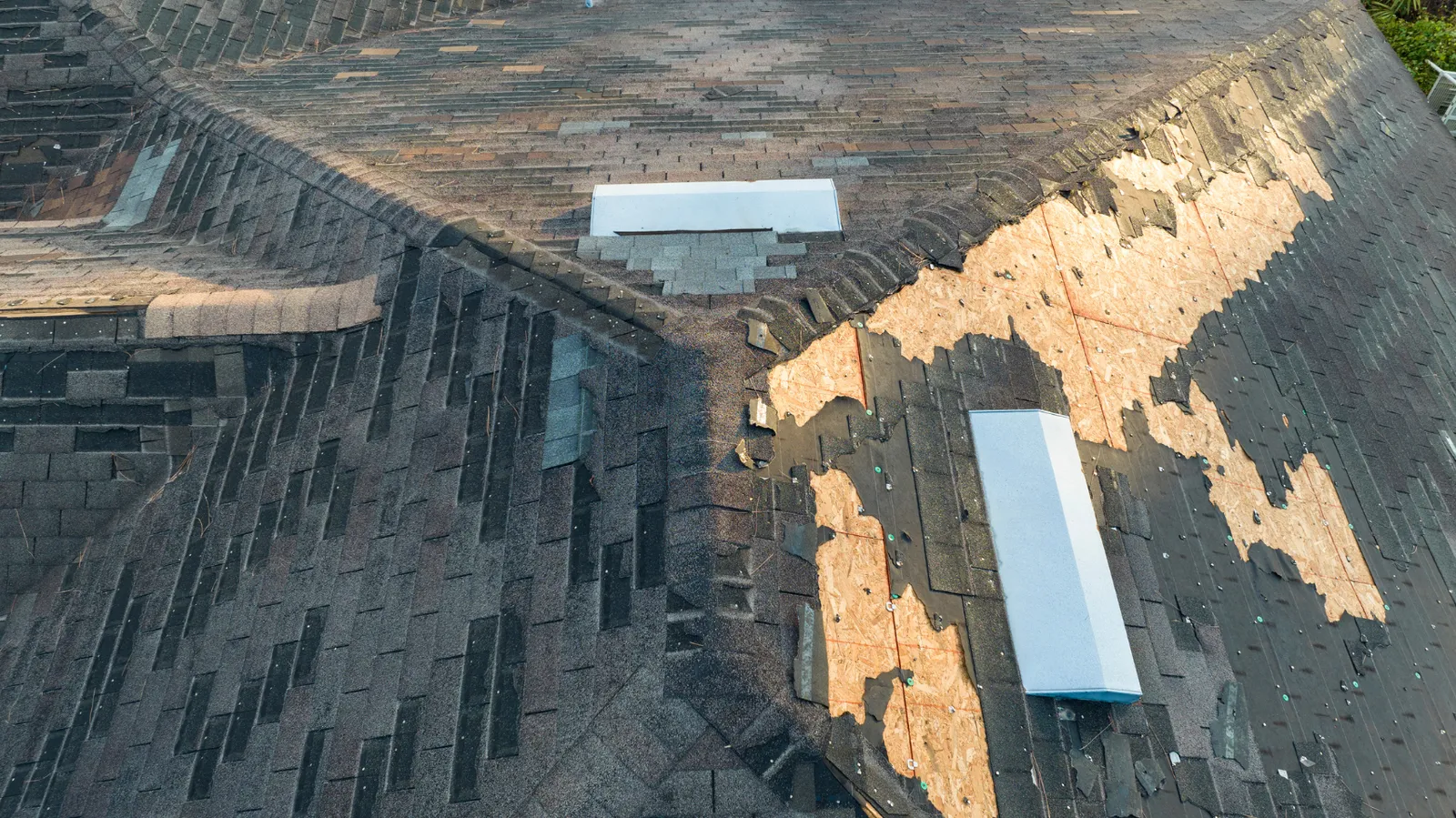 Roof skylights with exposed plywood patches beside them viewed from the air